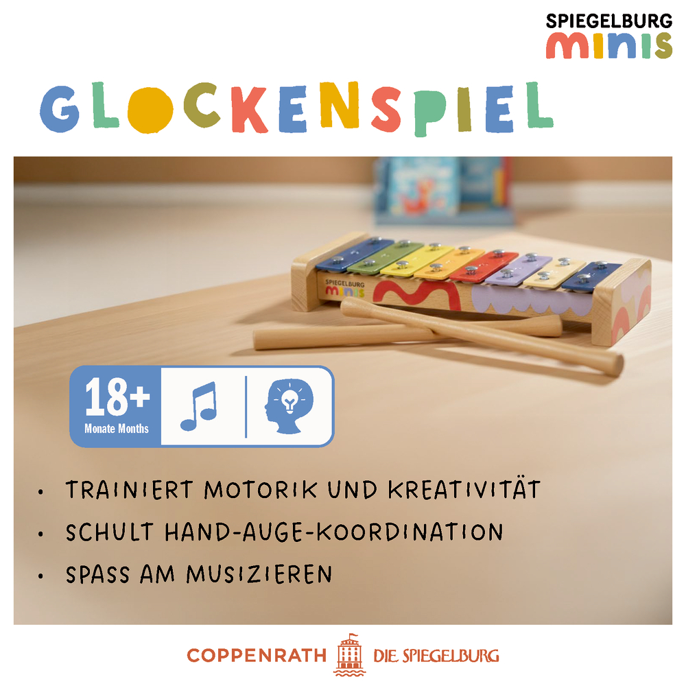 Buntes Glockenspiel mit Schlägeln auf einem Tisch, Etikett mit Angabe 18+ Monate und verschiedenen Symbolen.