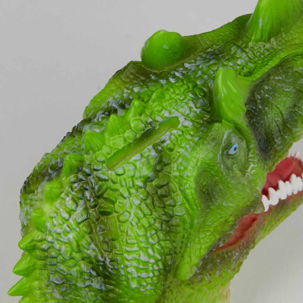 Nahaufnahme eines grünen Dinosaurierspielzeugs mit Schuppenstruktur und offenem Maul mit weißen Zähnen.