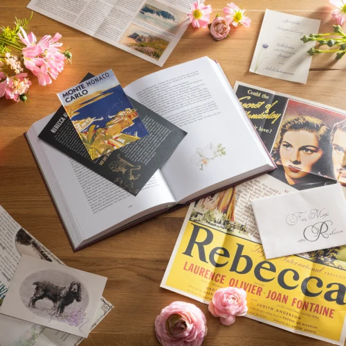 Darstellung der aufgeschlagenen Coppenrath Schmuckausgabe Rebecca umgeben von Blumen, Zeitungsartikeln und Briefen.