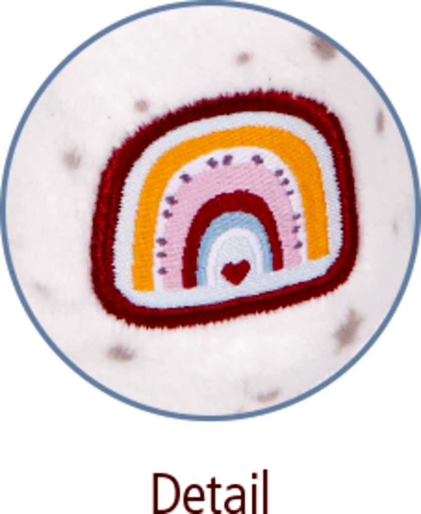 Nahaufnahme eines gestickten Regenbogens mit einem kleinen Herzen auf weißem, gepunkteten Stoffhintergrund.