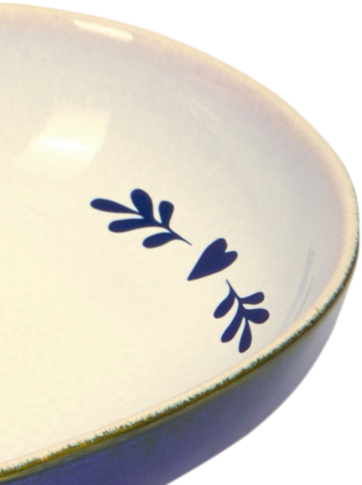 Nahaufnahme der dunkelblauen Verzierung eines weißen Tellers.