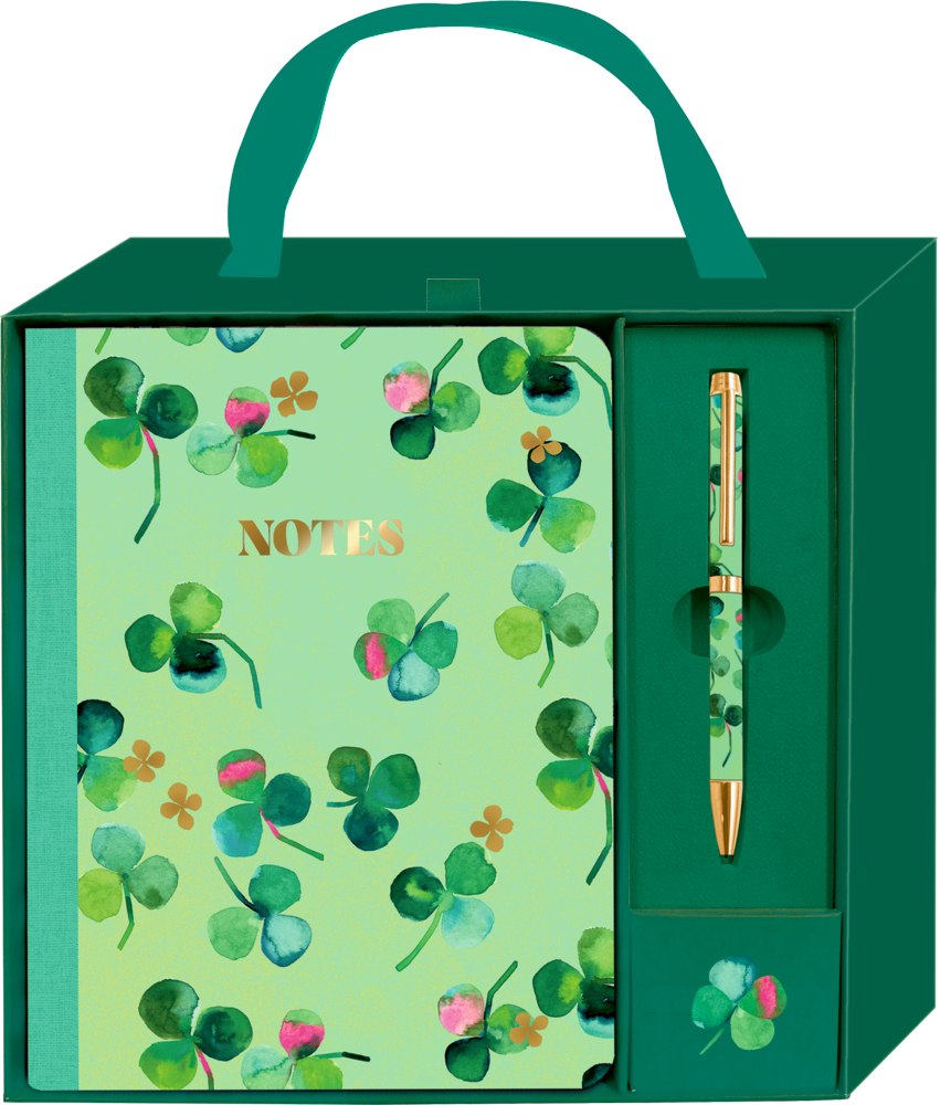 Grüne Geschenkbox mit einem Notizbuch mit Aufschrift NOTES und passendem Stift, beide mit Kleeblattmotiv.