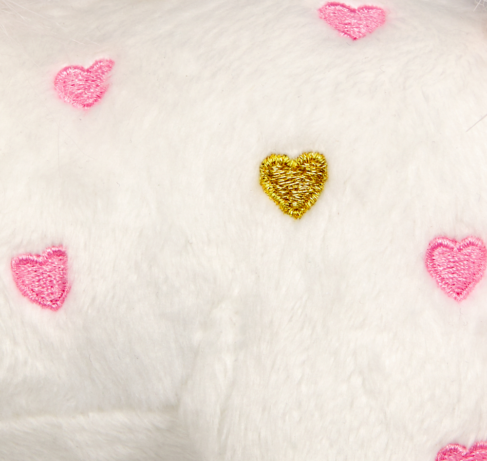 Nahaufnahme von weißem Plüschstoff mit rosa gestickten Herzen und einem gold gestickten Herz.