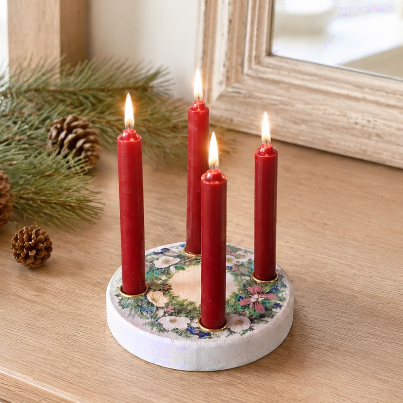 4 rote Kerzen auf einem hellen, kreisrunden Ständer mit weihnachtlicher Motivik.