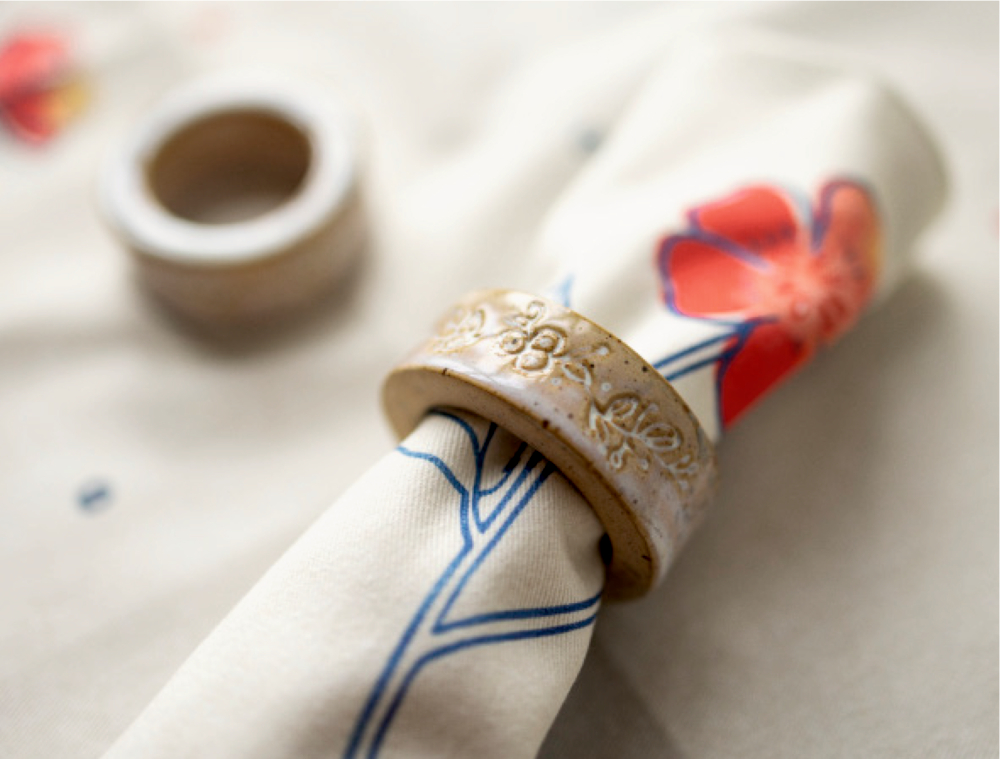 Keramikserviettenring mit hineingesteckter, rustikaler serviette.