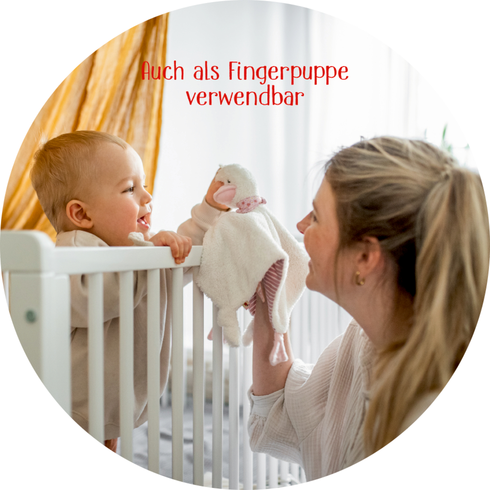 Ein Baby in einem Kinderbett lächelt eine Frau mit einer Entenhandpuppe an; darüber erscheint ein deutscher Text.