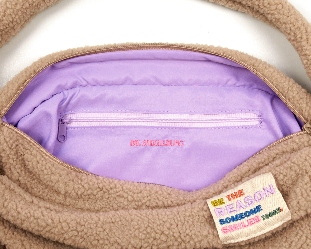 Beige Fleece-Tasche mit lavendelfarbenem Innenfutter und Patch: „Sei der Grund, warum heute jemand lächelt.“.