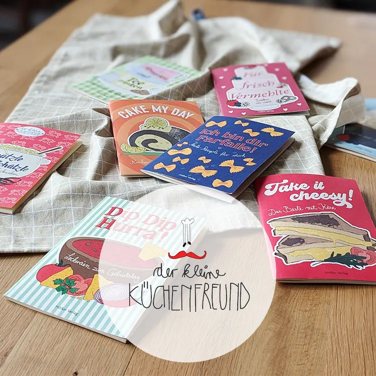 Viele kleine, dünne Büchlein liegen verstreut auf einem Tisch. Dazu das Logo "Der kleine Küchenfreund"