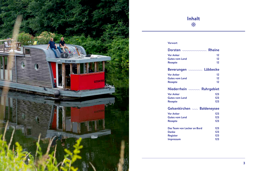 Ein Hausboot mit Menschen auf dem Dach treibt auf einem ruhigen Fluss, umgeben von grünen Bäumen.