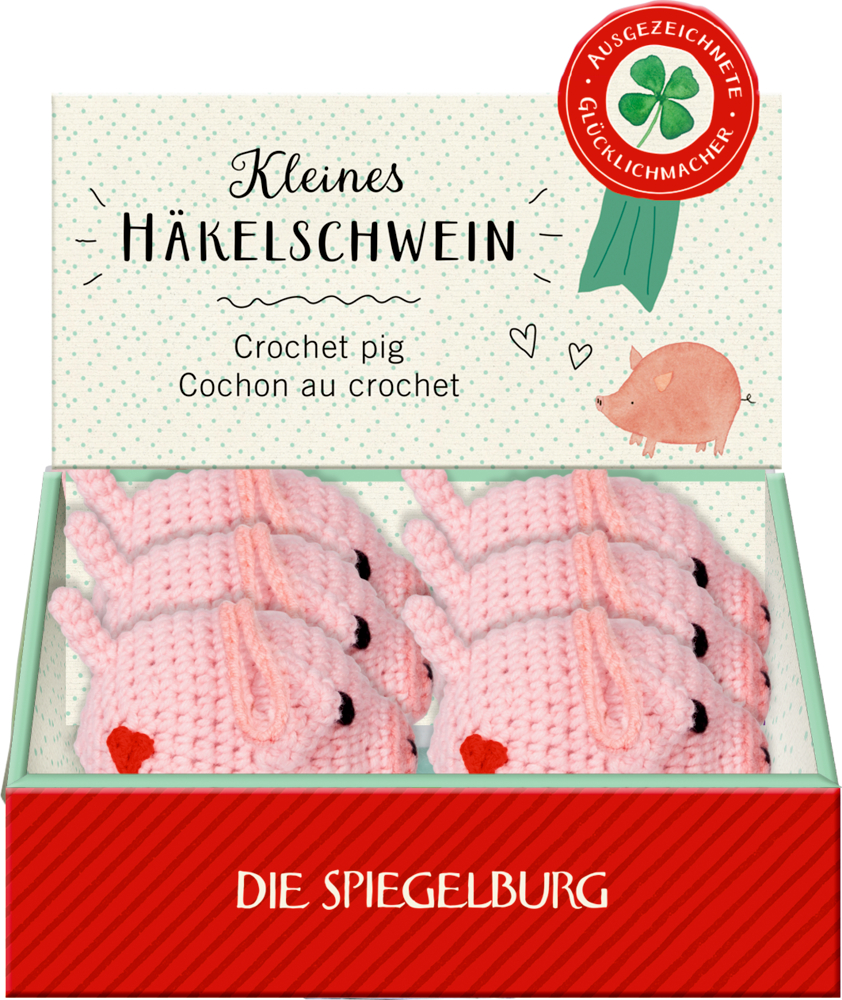 Schachtel mit kleinen rosa gehäkelten Schweinchen mit dem Text „Kleines Häkel-Schwein“ und dem „Die Spiegelburg“-Branding.