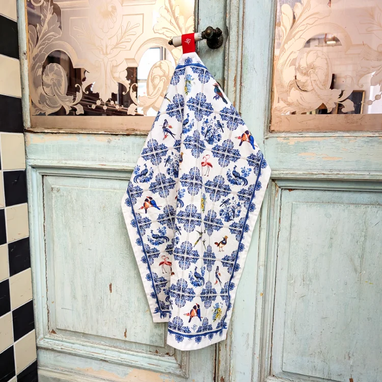 Weißes Tuch mit blauen Nostalgiemustern an einer alten Tür mit kunstvoll geschliffenen Glasscheiben.