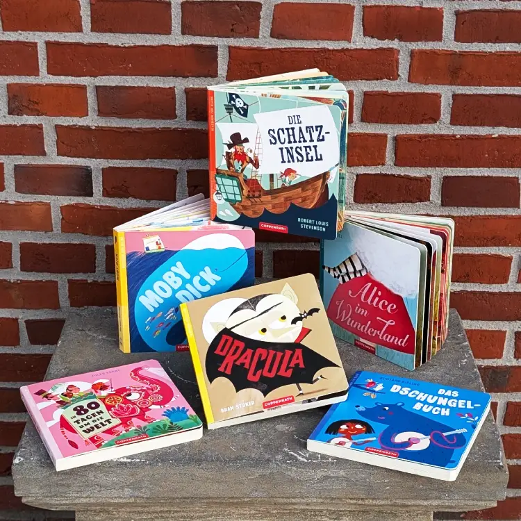 Mehrere Bilderbücher mit Literaturklassikern auf einem Steinsockel.