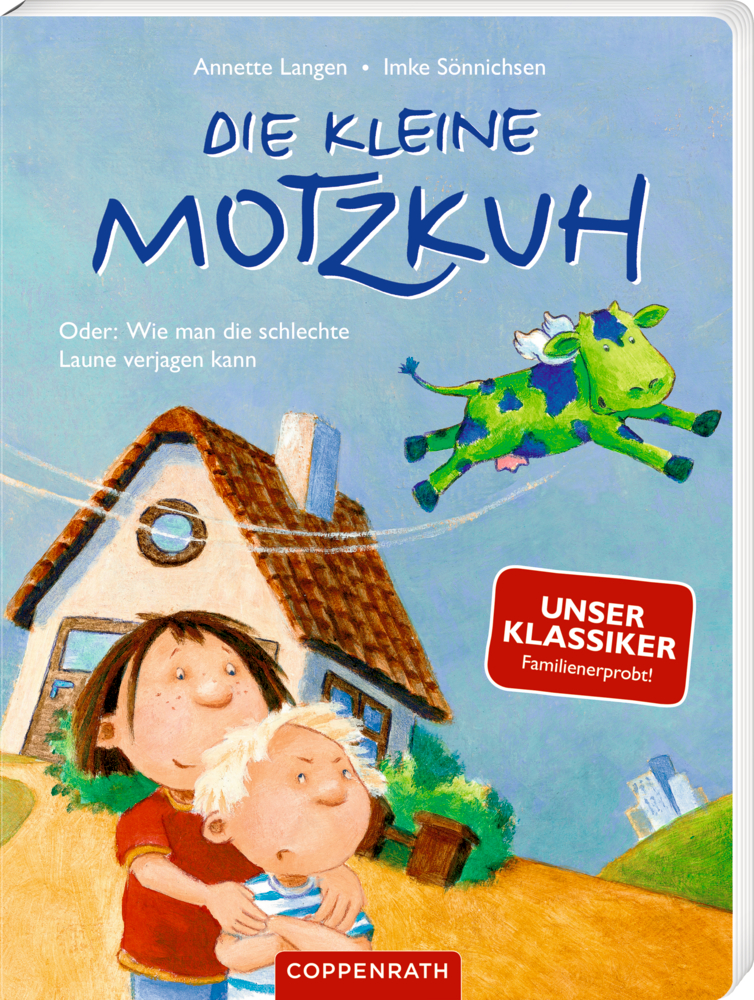 Die kleine Motzkuh (Pappbilderbuch) Buchcover mit zwei Kindern, die vor einem Haus stehen. über ihnen fliegt eine grüne Kuh. Auf einem roten Schild steht „Unser Klassiker“.