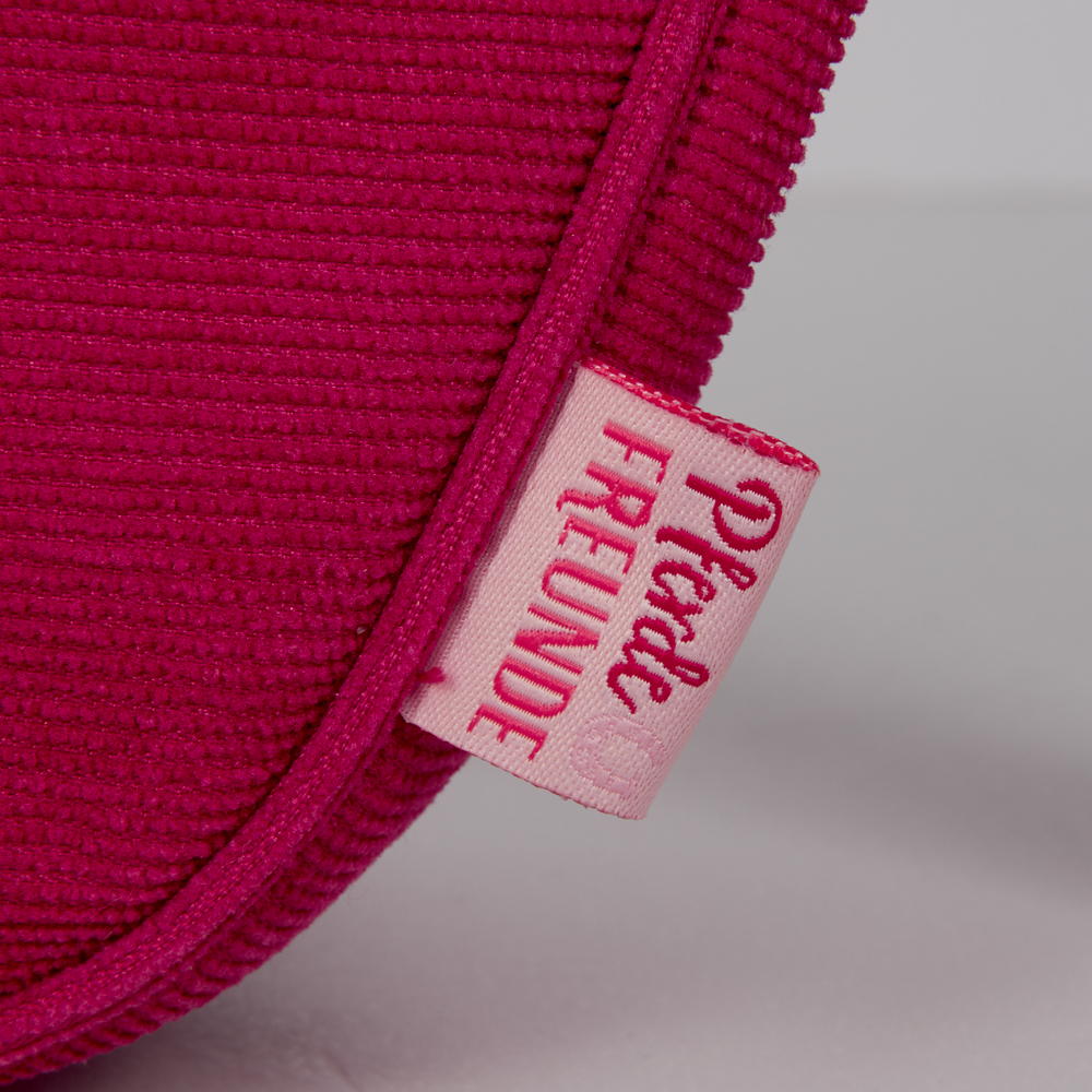 Nahaufnahme eines pinken Stoffbeutels mit einem „Pinke FREUNDE“-Etikett in rosa und roter Schrift.