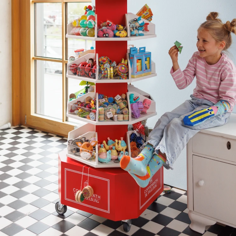 Mädchen spielt mit kleinen bunten Geschenken aus einer Roten Drehsäule