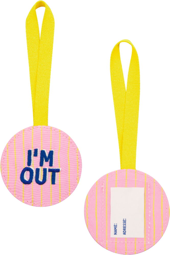 Zwei runde, pinke Kofferanhänger mit gelben Bändern; einer zeigt IM OUT, der andere ein Namensfeld.