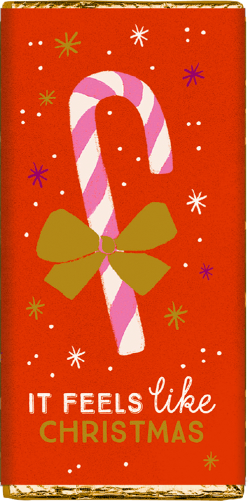 Rote Verpackung mit rosa-weißer Zuckerstange, goldfarbener Schleife und dem Text „It feels like Christmas“.