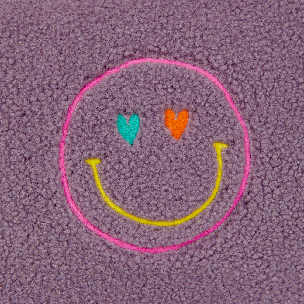 Lilafarbenes Vlies mit rosa umrandetem Smiley-Gesicht, blauen und orangefarbenen Herzaugen, gelbem Lächeln.