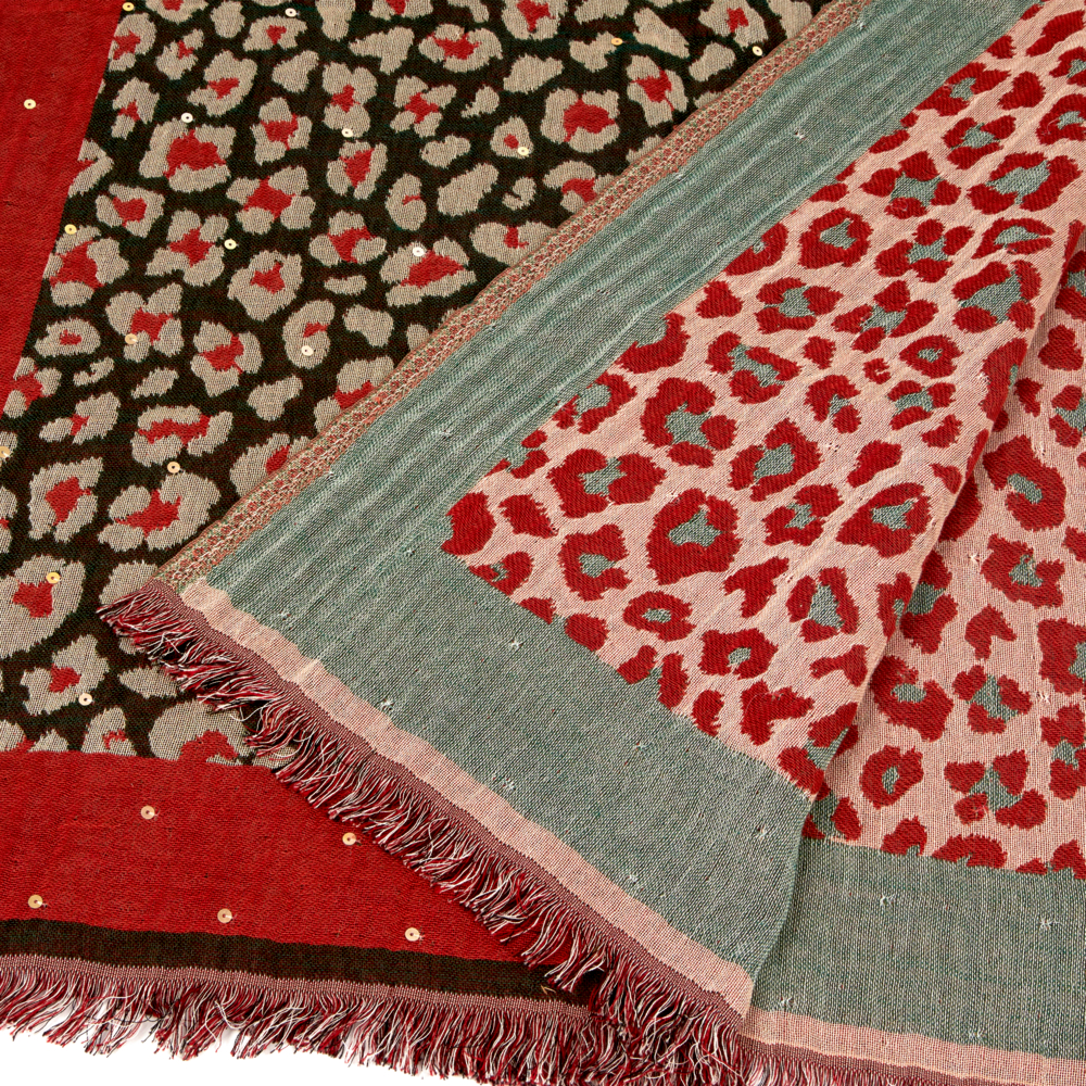Nahaufnahme eines Fransenstoffs mit rotem, grauem und braunem Leopardenmuster und metallischen Punkten.