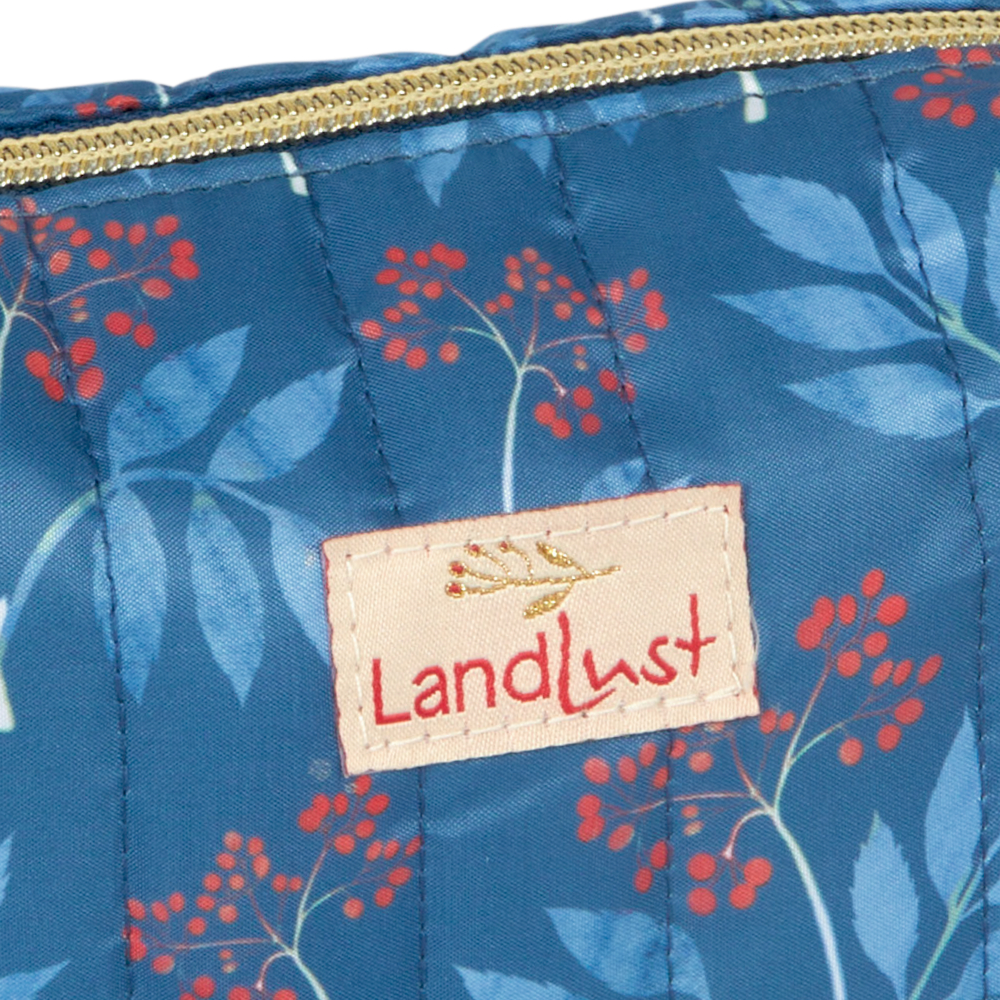 Blauer Stoffbeutel mit rotem Beeren-/Blattmuster, goldenem Reißverschluss und aufgenähtem Landlust-Etikett.