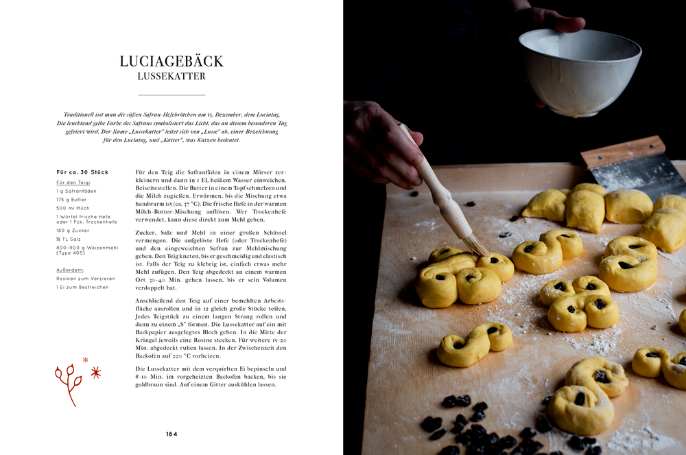 Die Hände einer Person verzieren Gebäck auf einer bemehlten Oberfläche mit Rosinen. Links daneben ein Rezept.