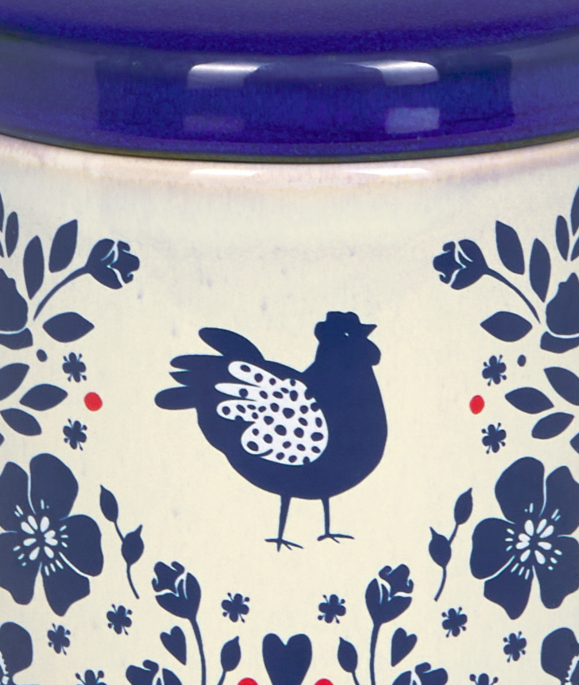 Nahaufnahme eines blauen Huhns und weiterer Ornamente auf einer weißen Dose.