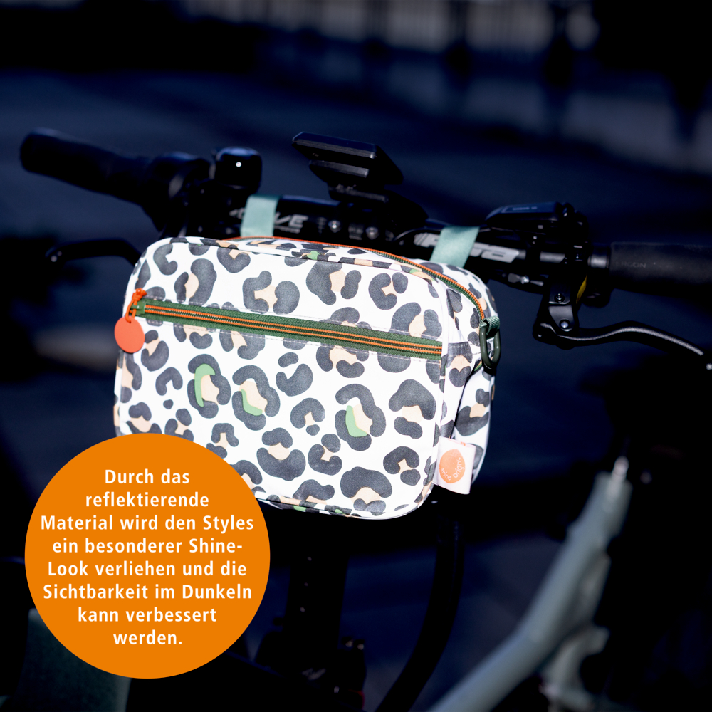Rechteckiges Täschchen mit Animal Print, lichtreflektierendem Stoff und Reißverschluss außen an einem Lenker befestigt.