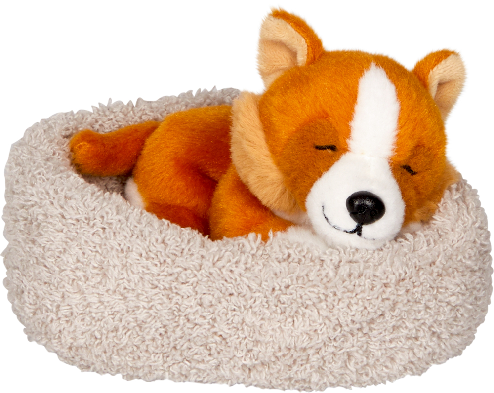 Ein orangefarbener Plüschhund schläft in einem weichen, beigen, ovalen Plüschtierbett.