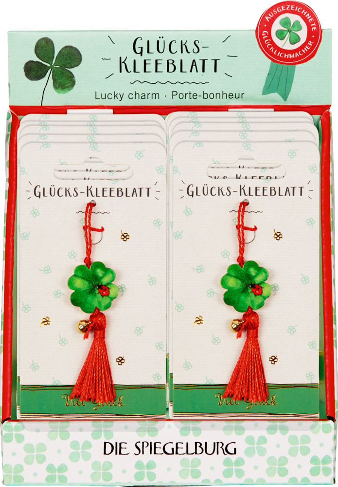 Schachtel mit Glücksklee-Anhängern auf Karten, jede mit einer roten Quaste und einem kleinen goldenen Glöckchen.