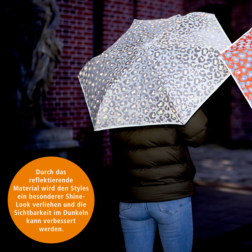 Person mit reflektierendem Regenschirm mit Leopardenmuster.