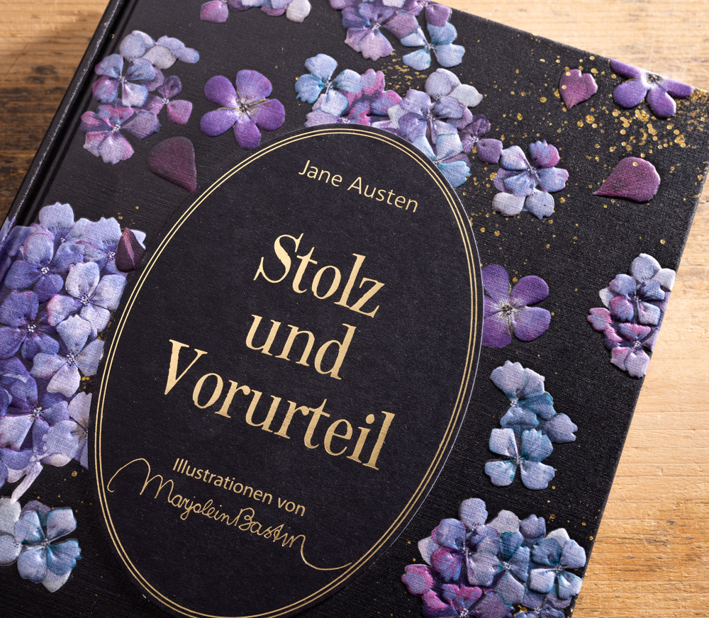 Cover Roman Stolz und Vorurteil Jane Austen Nahaufnahme des Covers von Stolz und Vorurteil mit goldener Schrift und violettem Blütenrelief.