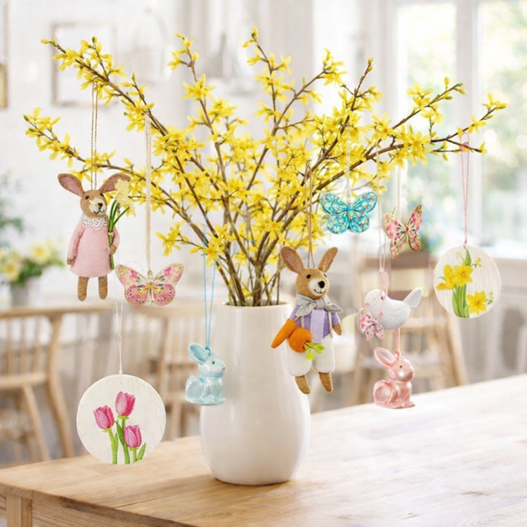 Forsythia-Strauß in einer Vase mit Osteranhängern.