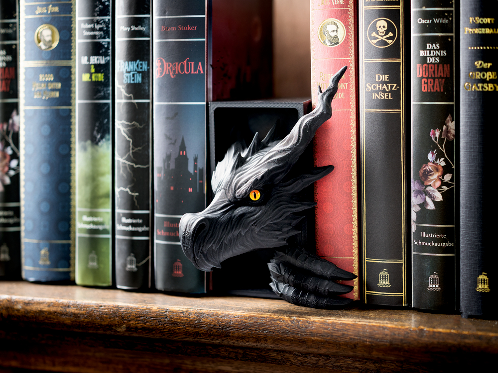 Schwarzer Drachenkopf mit gelben Augen ragt aus einer Bücherreihe klassischer Romane auf einem Holzregal hervor.