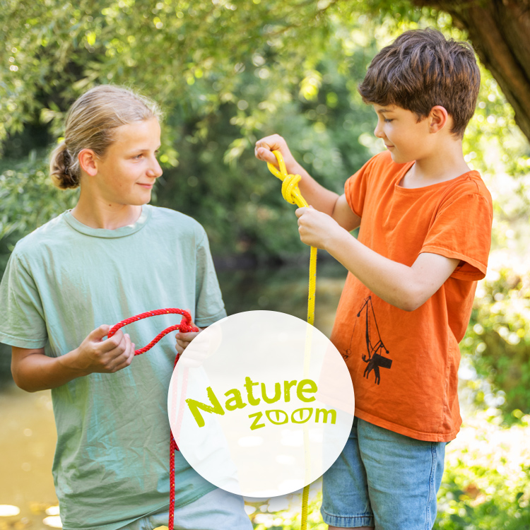 Zwei Jungs mit Seilen an einem Fluss.