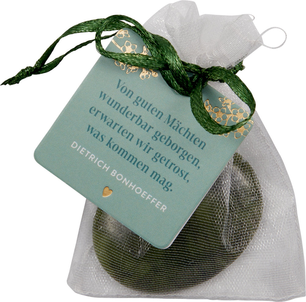 Weiße Geschenktüte aus Netzstoff mit einer grünen Karte mit einem Zitat von Dietrich Bonhoeffer.