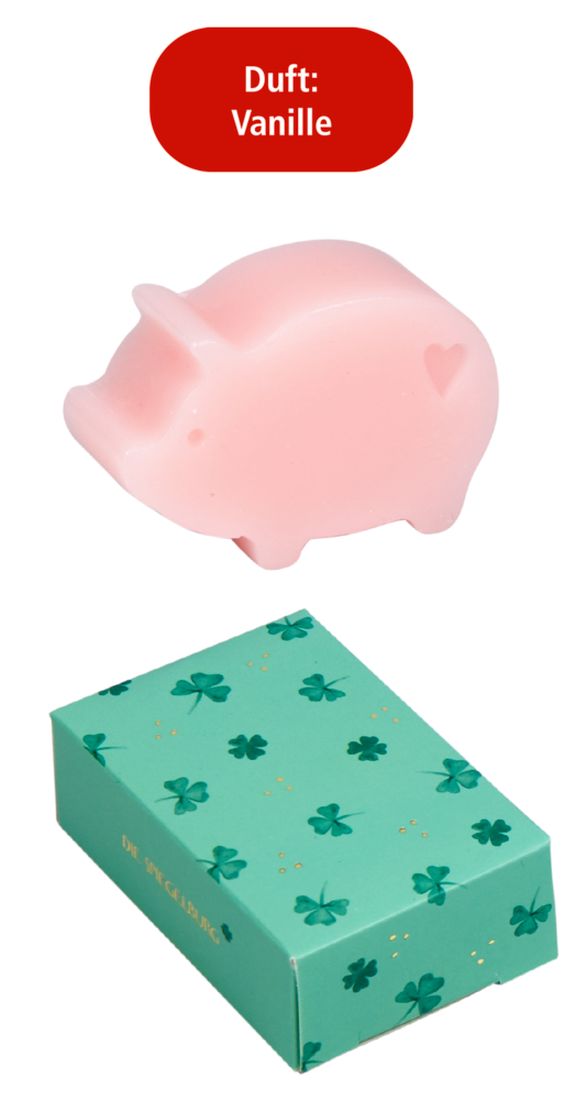 Rosa Seife in Schweinchenform mit Herzsymbol, rotes Textfeld „Duft: Vanille“, daneben grüne Schachtel mit Kleeblattmuster.