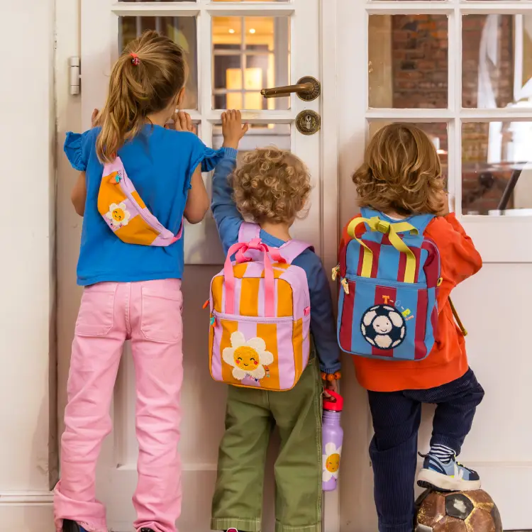 Kinder mit verschiedenen Rücksäcken und Hipbags schauen durch ein Fenster