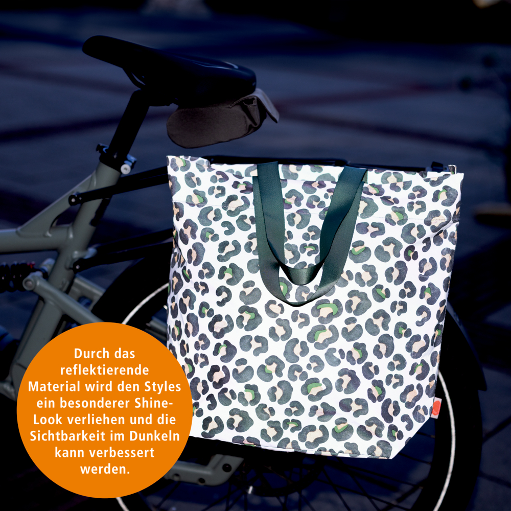 Reflektierende Leo-Tasche am Fahrrad bei Nacht; oranger Kreis mit Sichtbarkeits-Hinweis.