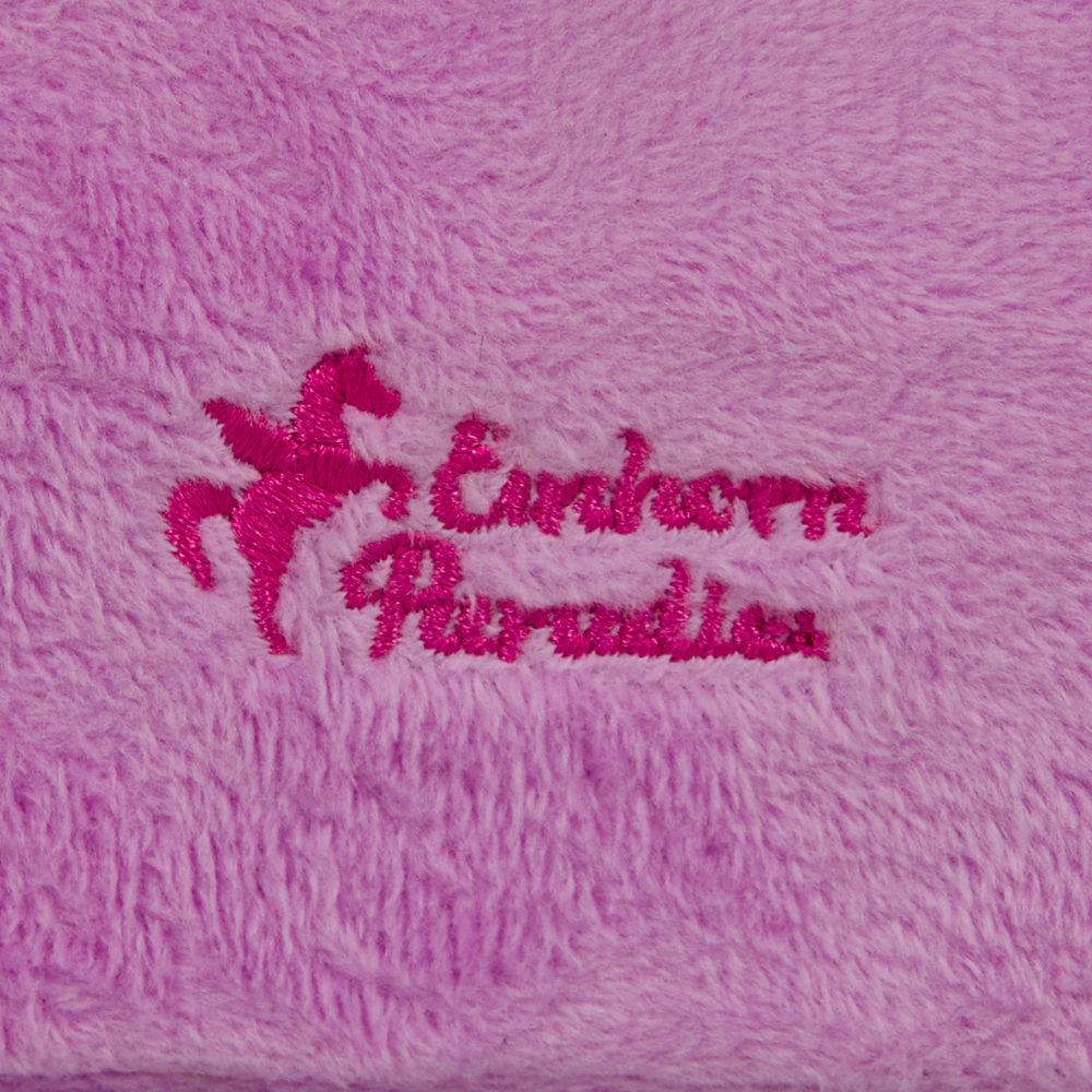 Rosa gesticktes Einhorn Paradies Logo auf weichem, flauschigem, helllila Stoff.