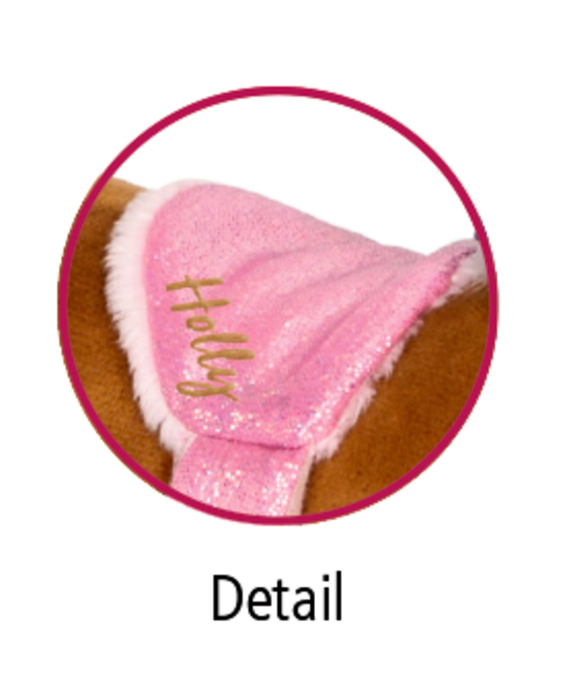 Nahaufnahme eines rosa Sattels mit dem aufgestickten Wort „Grace“ an einem Plüschtierkörper.